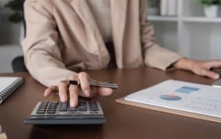 Person calculating finances with charts and calculator.