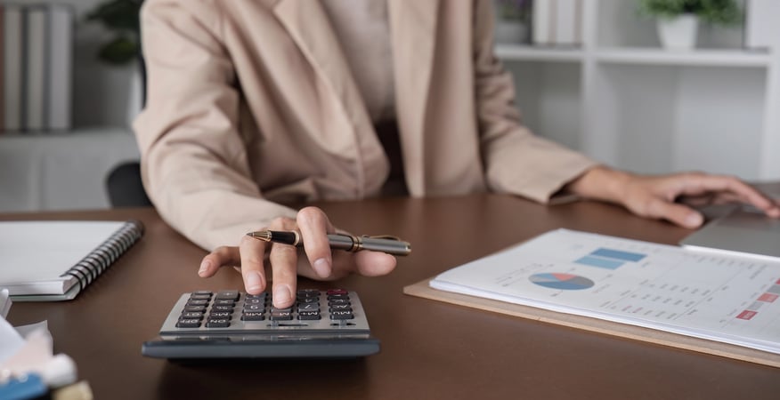 Person calculating finances with charts and calculator.