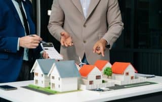 Real estate agents reviewing property models with financial calculations, highlighting how bookkeeping consultancy supports scaling real estate businesses.