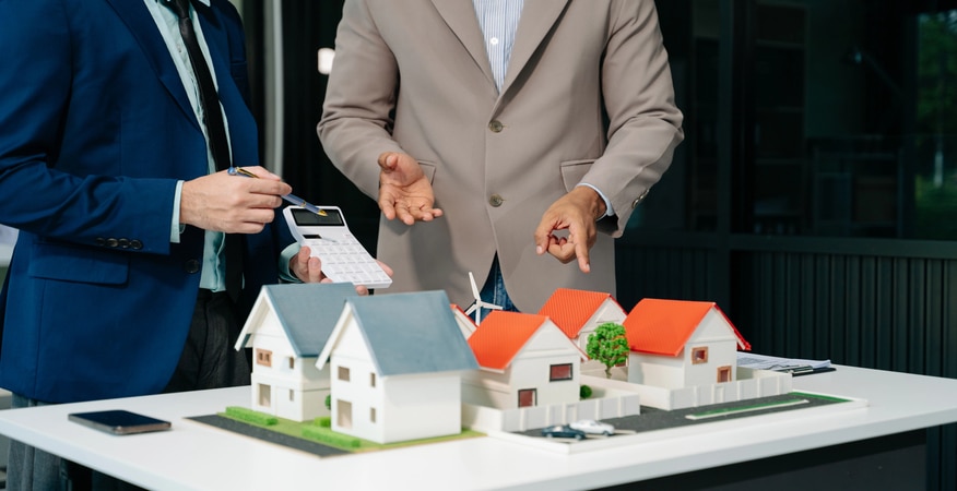 Real estate agents reviewing property models with financial calculations, highlighting how bookkeeping consultancy supports scaling real estate businesses.