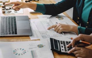 People analyzing financial documents and using calculator.