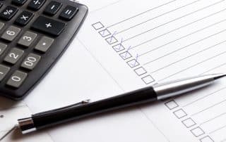 A checklist with checkmarks, calculator, and pen symbolizes the QuickBooks Cleanup Checklist: How to Get Your Books in Order with DK/RK Services.