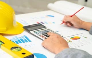 Person calculating construction project costs with charts.