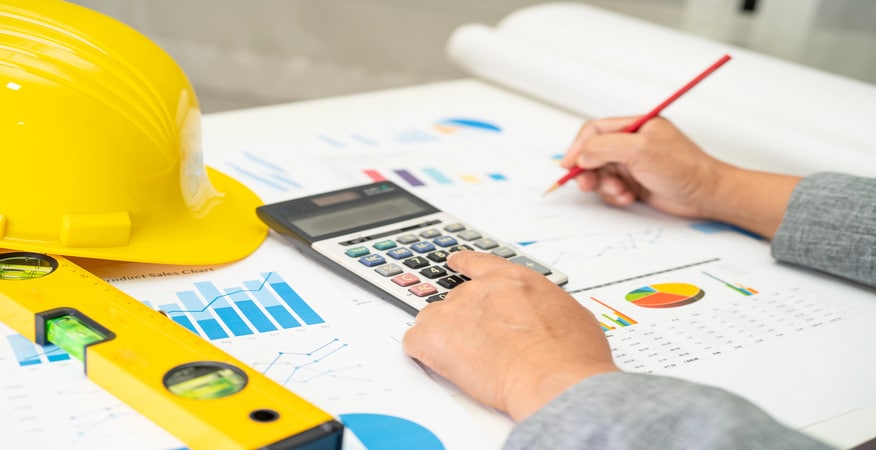 Person calculating construction project costs with charts.